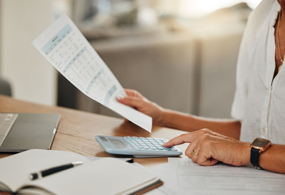 Gestora de RH analisando documentos sobre FGTS e folha de pagamento em seu computador, com gráficos de conformidade trabalhista ao fundo, representando controle e segurança na gestão de benefícios.